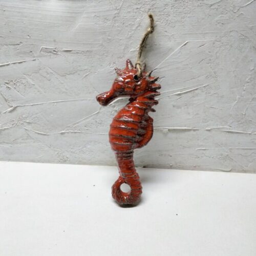 A close-up image of a meticulously handcrafted ceramic red seahorse with intricate details, showcasing its vibrant color and unique artisanal craftsmanship